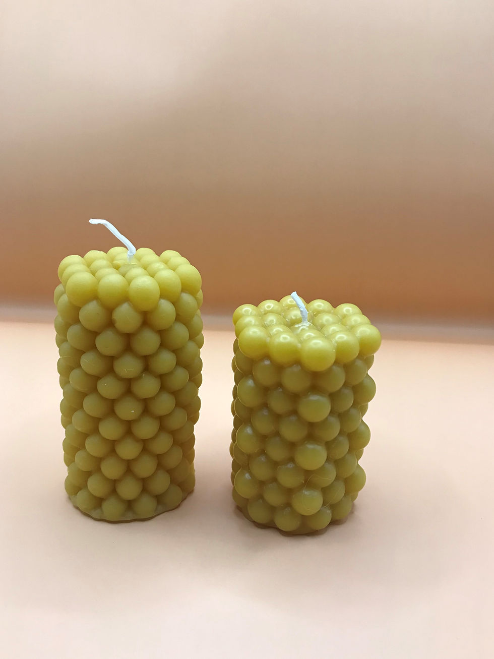 Two beeswax candles with textured surfaces