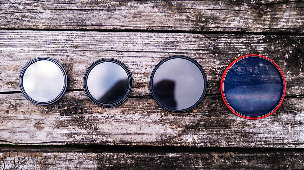 Four circular camera lens filters on weathered wooden planks, including a red-rimmed blue filter and mirrored reflections