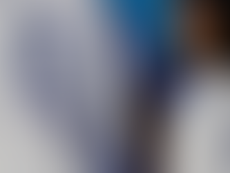 A person wearing a white t-shirt with a graphic of a duck and the text "Surprise mother quacker". Another person in a white shirt stands beside them, both smiling against a blue background.