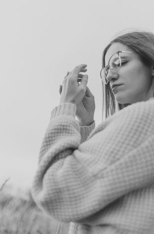 Junge Frau in Brille berührt Hände, Blick nach unten, draußen, Selbstliebe Fotoshooting Helmstedt, softgoldenpictures