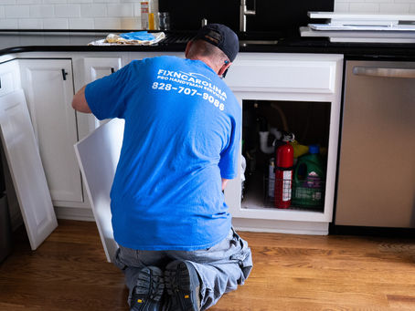 Handyman installing cabinet doors under kitchen sink in Asheville, NC