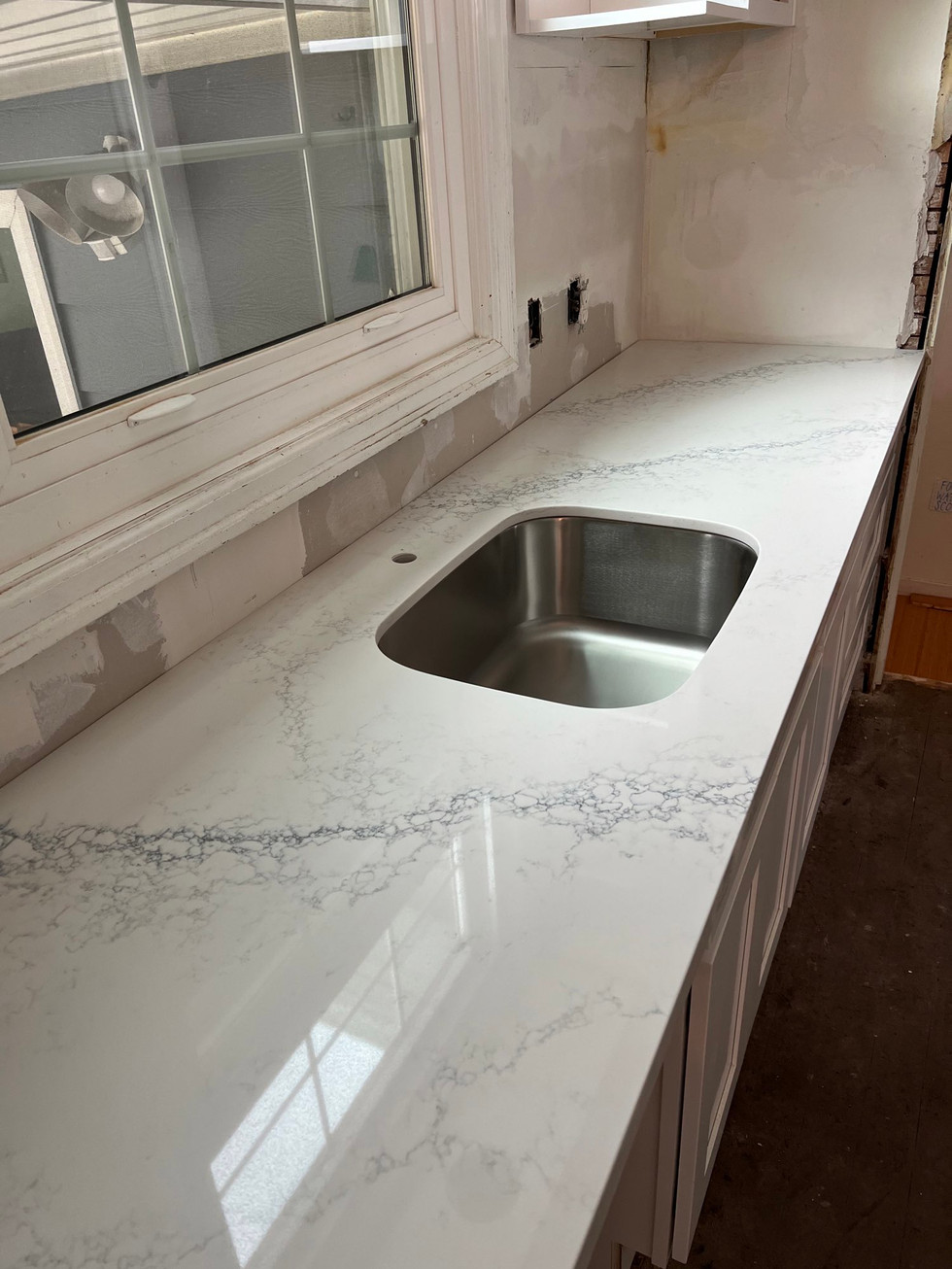 a white counter top with a stainless steel sink