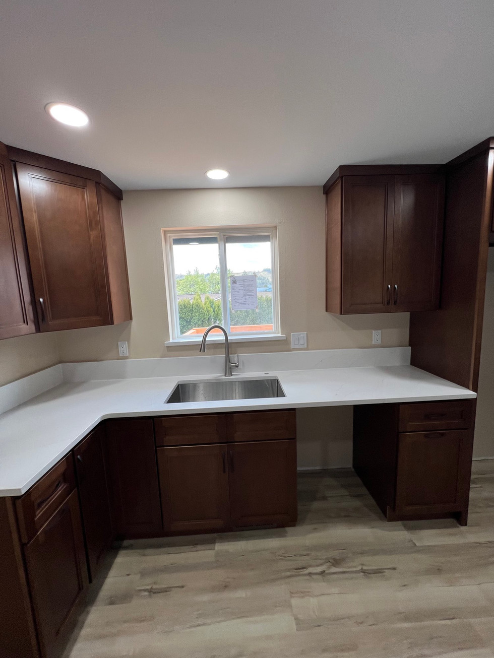 a kitchen with brown cabinets and a stainless steel sink