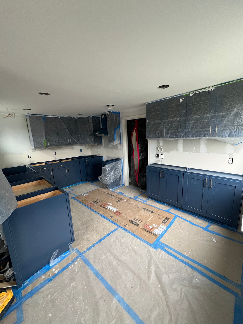 a kitchen under construction with blue cabinets and a cardboard box on the floor