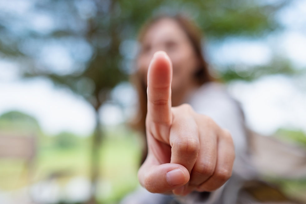 Alt text: The Neuroscience Behind EMDR Therapy, blurry image of a woman sitting on a bench outside raising her left index finger to the camera.