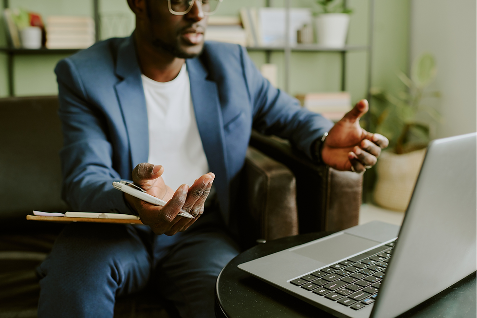 A therapist in a blue blazer gestures openly with both hands while engaged in a virtual consultation, conveying thoughtful explanation and collegial exchange.