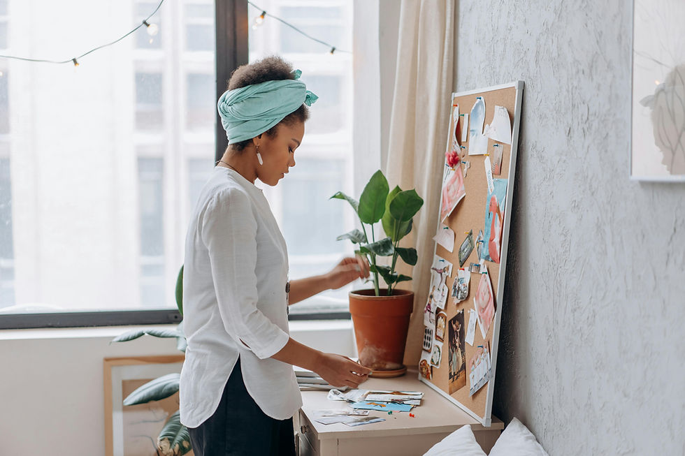 Alt text: Exploring the IFS Model, image of a woman wearing a white blouse and blue headband pins cut-out pictures on a cork board filled with other cut-out pictures.