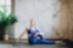 Benefits of yoga, yoga for trauma recovery. A woman in blue athletic clothing doing a seated yoga pose looking calm.
