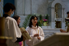 Woman in baptismal robes holding candle on alter