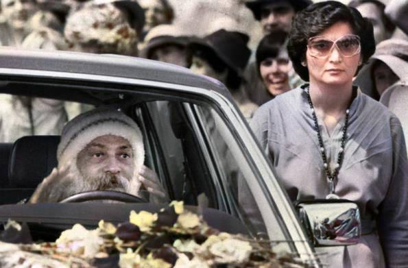 Bhagwan Shree Rajneesh driving one of his many Rolls-Royces, his lieutenant and chief enforcer Ma Anand Sheela always at his side.