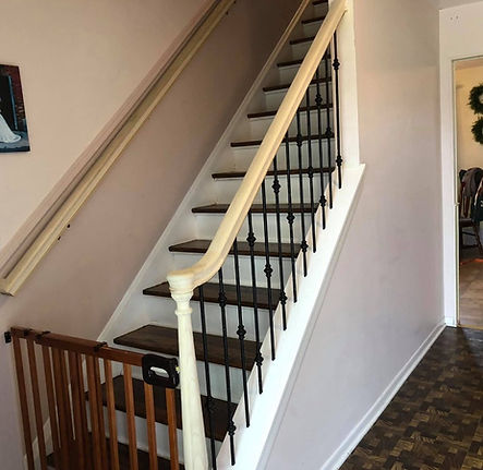 Wooden Stairs with black railings, baby gate, and wall picture.