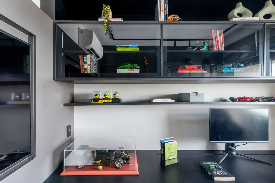 Home office moderno com prateleiras pretas decoradas com miniaturas de carros, livros e plantas.