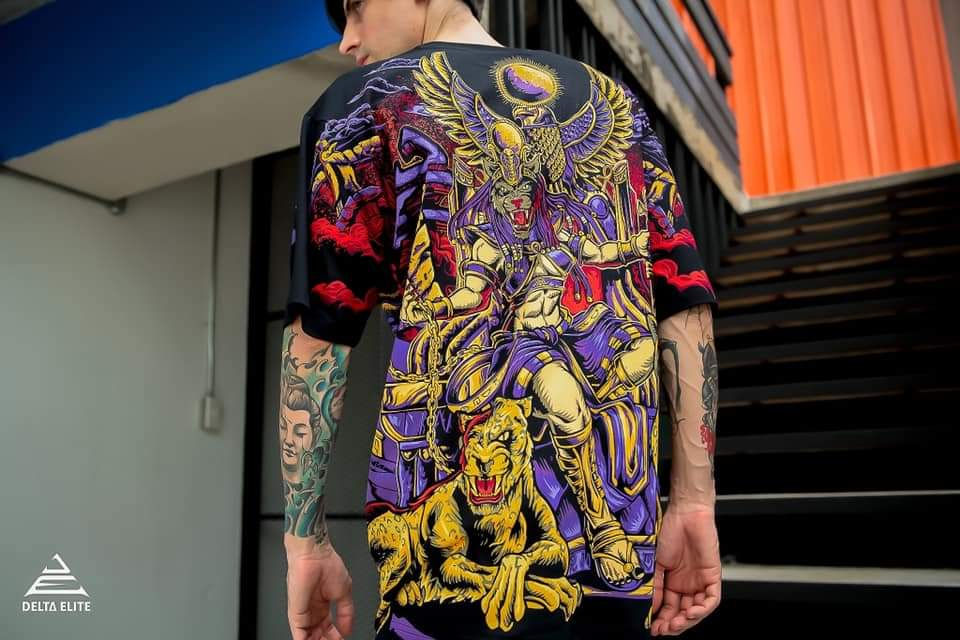 A photo of a man wearing a Delta Elite branded t-shirt with a Sekhtet design illustrated by Mad Matt Design.