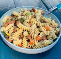 A colorful pasta salad in a light blue bowl.