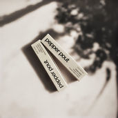 AI-generated product mockup of two boxes of lip gloss, shown on a beige surface with soft tree-shadow lighting