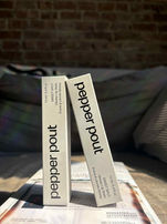 Image of two lip gloss boxes in natural indoor light against a bedroom background before AI styling.