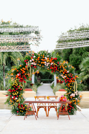 Outdoor wedding ceremony setup with colorful floral arch at Valentin Imperial Riviera Maya in Playa del Carmen