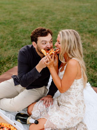 Playful couple sharing pizza at Loose Park in Kansas City