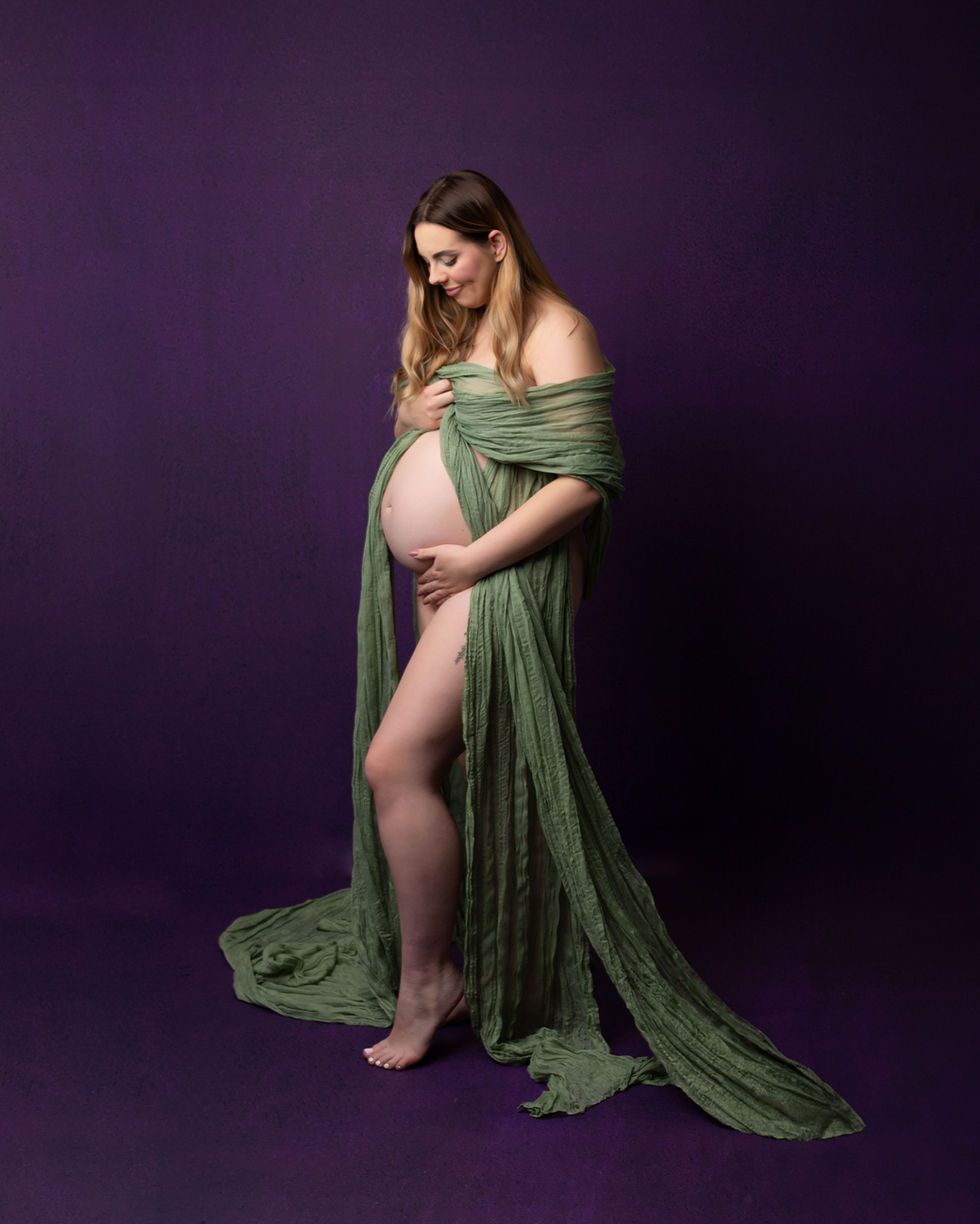 a pregnant woman is wrapped in a green cloth on a purple background