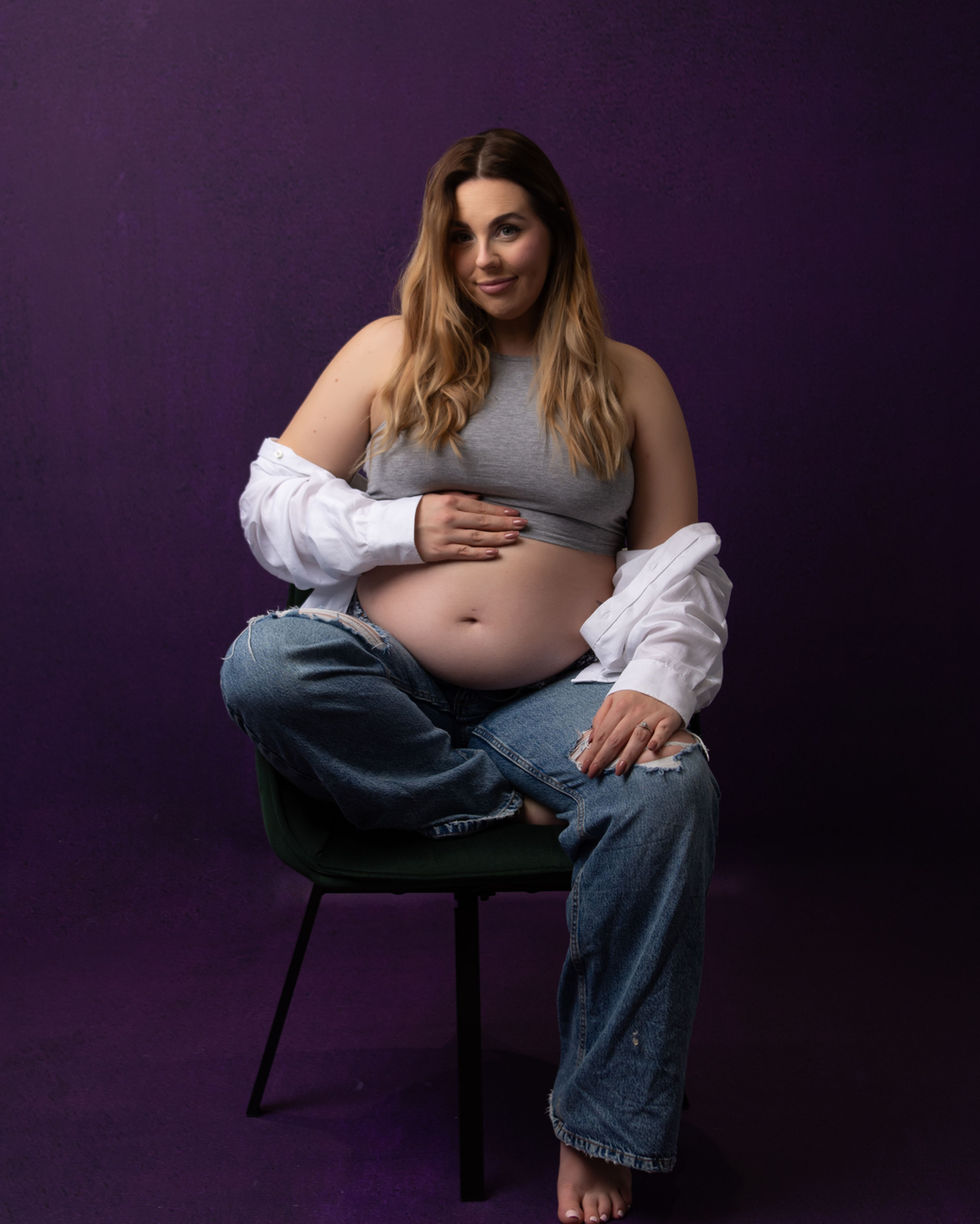 a pregnant woman is sitting in a chair holding her belly