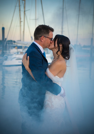 Newlyweds kiss on the marina surrounded by smoke at The Royal Southern Yacht Club, Hamble.