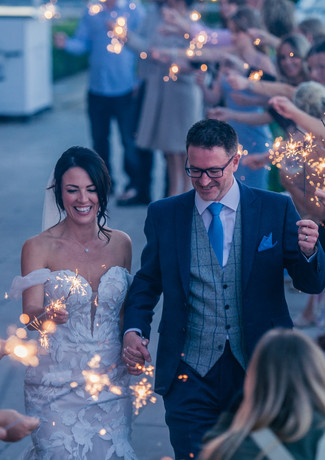Couple walk through guest sparkler arch at their wedding on the marina at The Royal Southern Yacht Club, Hamble.