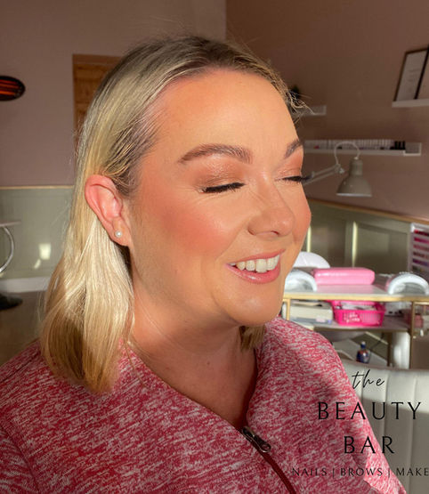 A lady smiling showing off her make up 
