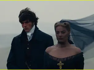 Two people in 19th-century attire stand on a misty plain. The woman's veil flows in the wind; both appear somber.