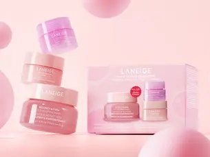 Laneige skincare trio in pink jars and box set against a pink background with floating pink spheres, creating a soft, inviting mood.