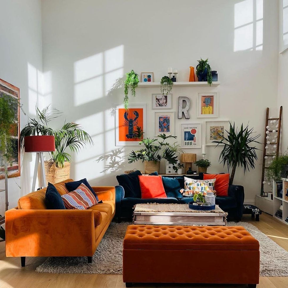 Bright living room with orange sofa, colorful cushions, plants, artwork, and sunlight casting window shadows. Cozy and vibrant ambiance.