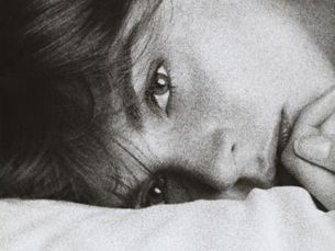 Woman lying on a pillow, gazing softly. Black and white image with a calm, intimate mood.