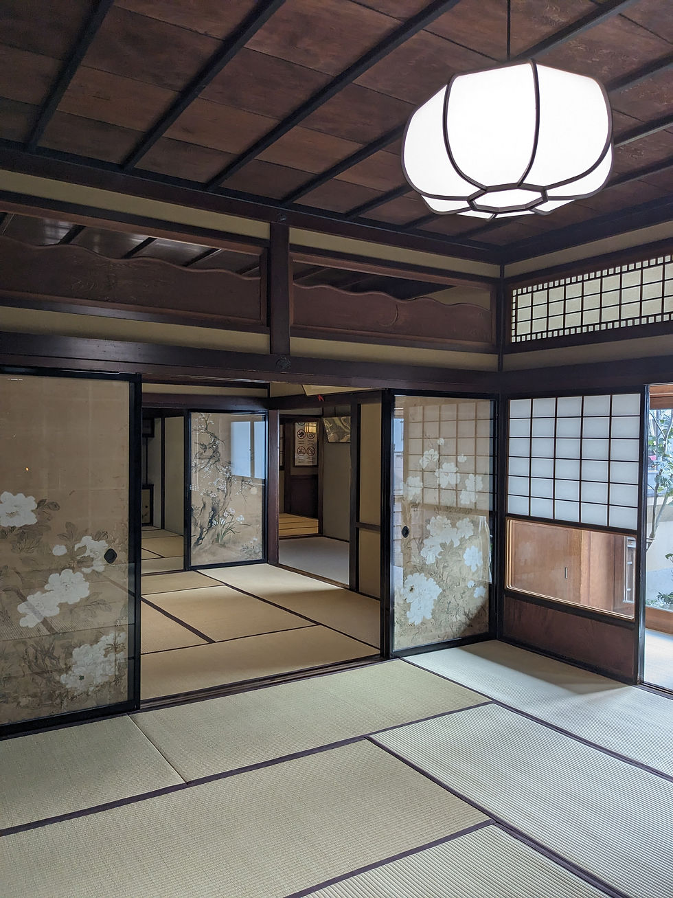 Traditional Japanese room with tatami mats, sliding doors with floral patterns, and a large white ceiling lantern, creating a serene ambiance.