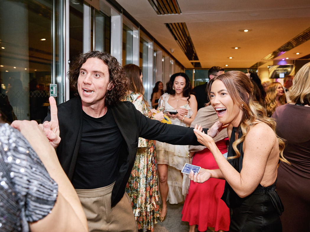 Lady having fun at a party in London, watching magician performing tricks.