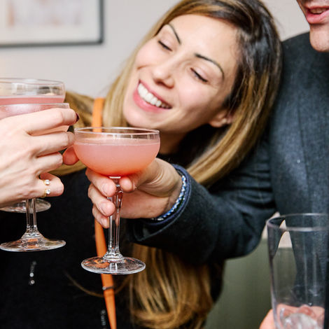 Smiling friends toast with pink cocktails