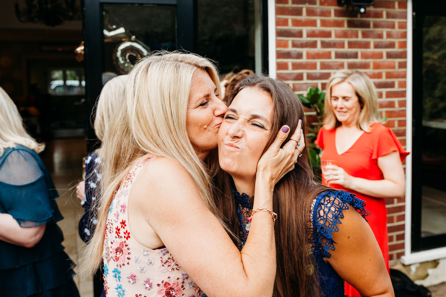 A lady kissing her friend at a party.