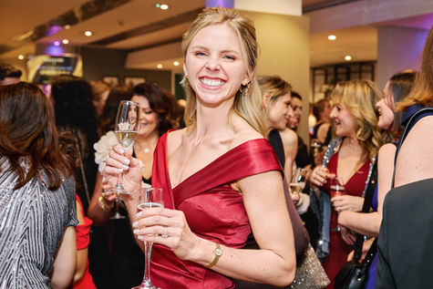 Smiling woman in red holding champagne at event