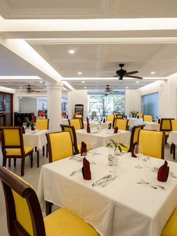 Modern restaurant dining room with yellow chairs.