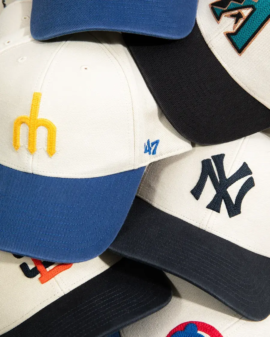 Close-up of assorted fitted baseball caps layered together, showcasing embroidered logos, colorways and premium details from Hat Club