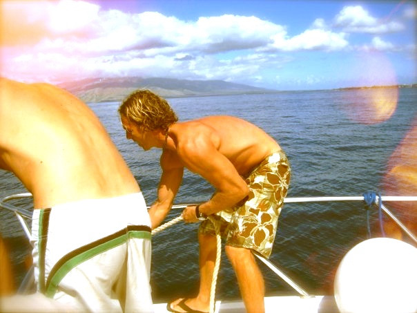Maui Hawaii dive boat crew man in beach shorts weighing anchor pulling rope