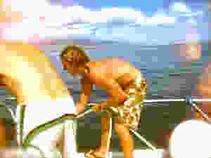 Maui Hawaii dive boat crew man in beach shorts weighing anchor pulling rope