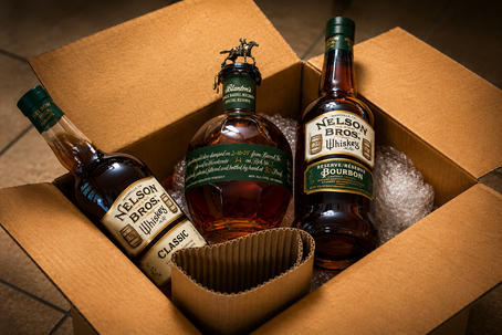 Three whiskey bottles in a cardboard shipping box with bubble wrap: Nelson Bros and Blanton's, warm amber tones.