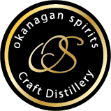 Black circular Okanagan Spirits Craft Distillery logo with gold monogram on a dark background