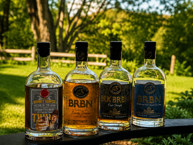 A selection of handcrafted bourbon-style whiskies from Okanagan Spirits Craft Distillery, displayed against a lush green garden backdrop.