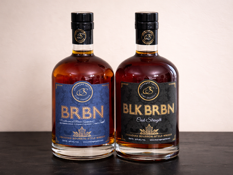 Two bottles of Okanagan Spirits Canadian bourbon-style whisky on a dark surface. Blue and black labels read "BRBN" and "BLK BRBN."