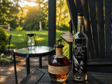 Two bourbon bottles, Blanton’s and Eagle Rare 10 Years, on a patio table in a sunny backyard.