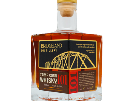 Bottle of amber Bridgeland Distillery Tabor Corn Whisky 101 with gold cap and bridge label.