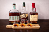 A tasting session featuring three iconic bourbons: Woodford Reserve, Buffalo Trace, and Maker’s Mark, elegantly showcased with three poured samples.