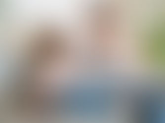 a child sat on a sofa with a laptop on her knee, talking to her mother