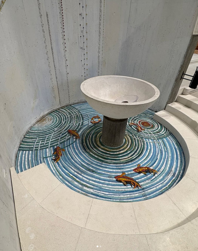 Decorazione musiva pavimentale per spazi liturgici (Arte Sacra).

Sviluppo Visivo e Iconografia: Il disegno si sviluppa in onde e cerchi concentrici che simulano il riverbero dell'acqua generato dalla sorgente del fonte. All'interno di queste geometrie fluide si muovono figure stilizzate di pesci – richiamo all'antico simbolo cristologico – che risalgono la corrente con vibrante dinamismo.