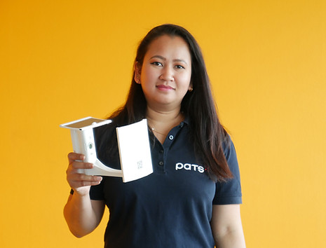Woman wearing a PATS shirt holding a Trap-Eye frame against an orange background